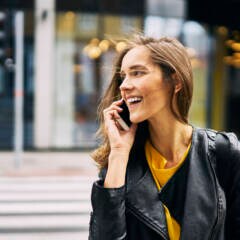 Rothaarige Frau telefoniert mit dem Handy auf der Straße