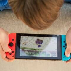 Kind liegt auf dem Boden und spielt mit der Nintendo Switch
