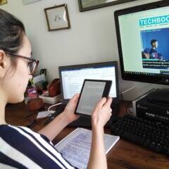 Amazon Kindle Oasis Test: Frau sitzt am Tisch und hält E-Book-Reader in der Hand