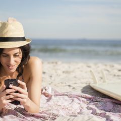 Frau am Strand mit Smartphone