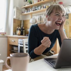 Frau lachend vor Laptop